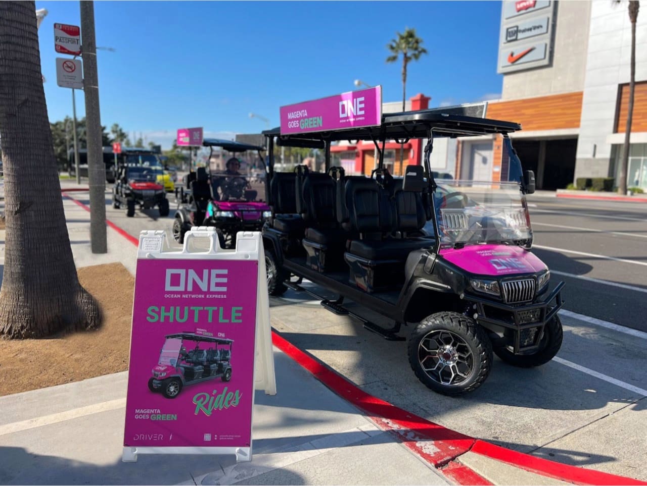 An Ocean Network Express branded shuttle cart beside its A-frame stop sign at the Long Beach Convention Center