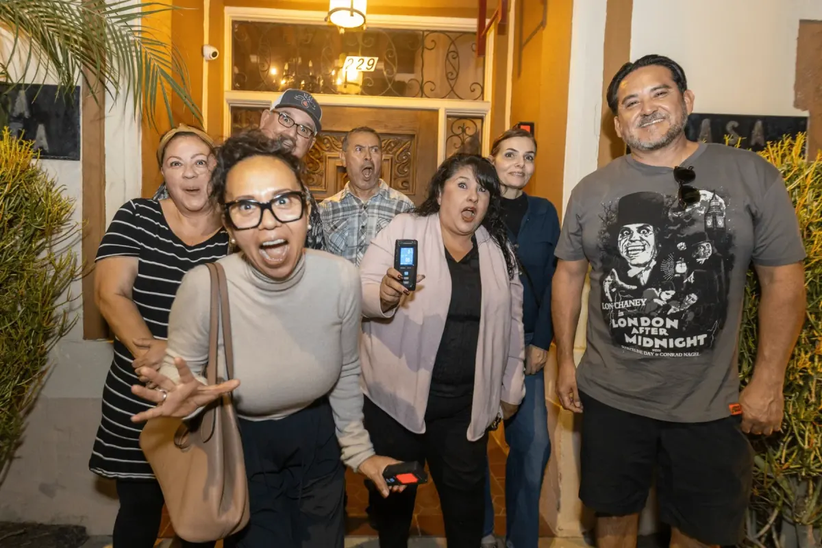 Guests with startled expressions posing together outside a doorway